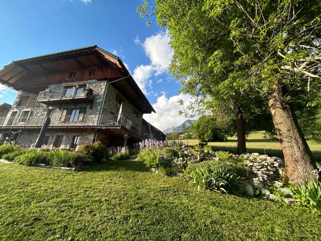 une maison avec un arbre et des fleurs devant elle dans l'établissement Les Chanterelles Montmin, à Plan Motmin