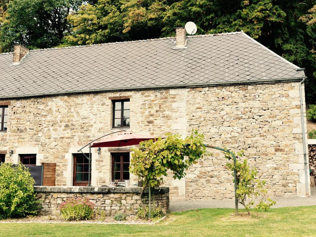 un edificio de piedra con un reloj encima en Gîte Basilic Havre de Paix pour 7 Personnes au Cœur de la Nature et près de la Meuse, en Vireux-Wallerand