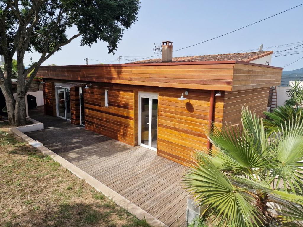 une maison en bois avec une terrasse dans une cour dans l'établissement Maison individuelle avec piscine et SPA, à Afa