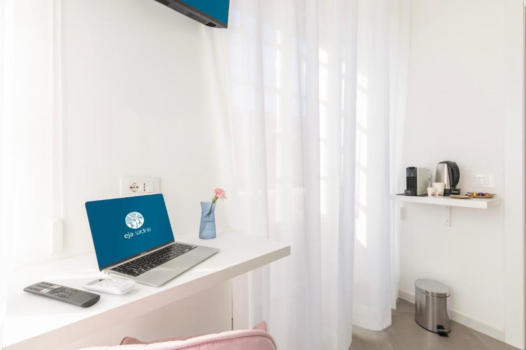 a laptop computer sitting on a white desk next to a window at Maddalena Rooms - Eja Sardinia in Cagliari