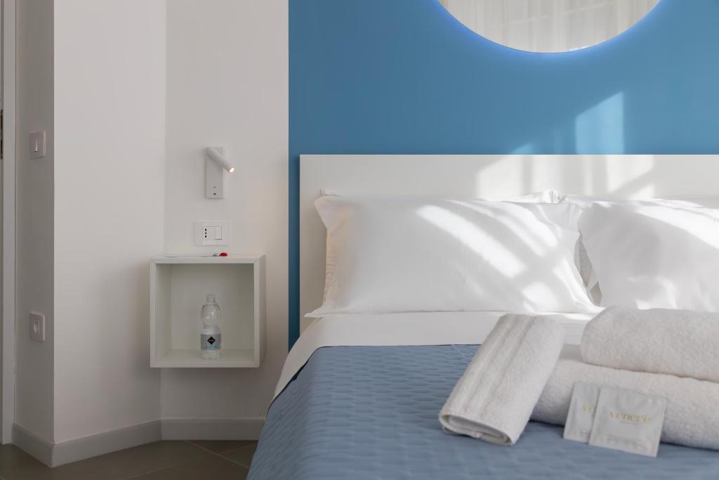 a bedroom with a bed with white sheets and towels at Maddalena Rooms - Eja Sardinia in Cagliari