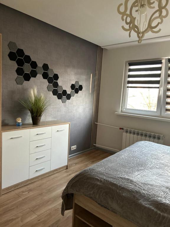 sypialnia z łóżkiem, komodą i oknem w obiekcie Apartament Wieluńska w Warszawie
