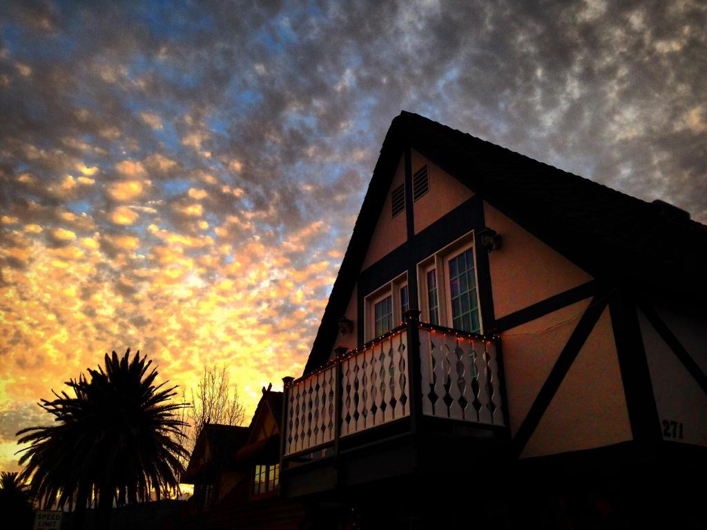 a building with a balcony with a sunset in the background at New Haven Inn in Solvang
