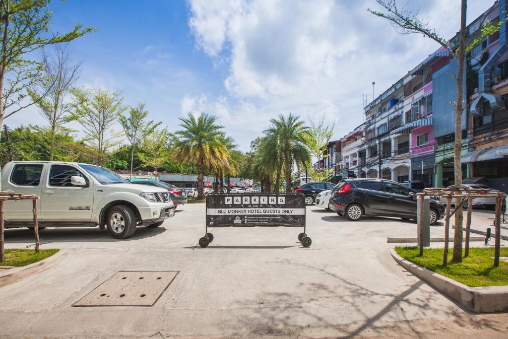 a sign in the middle of a parking lot with cars at Blu Monkey Hub and Hotel Phuket Town- Free All Day Coworking space in Phuket Town