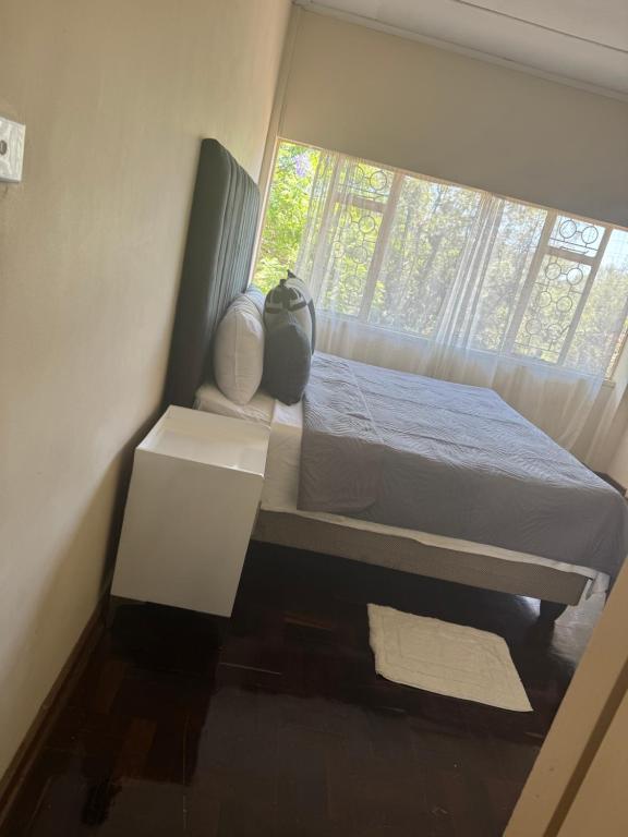 een kleine slaapkamer met een bed en een raam bij Calenstel in Bulawayo