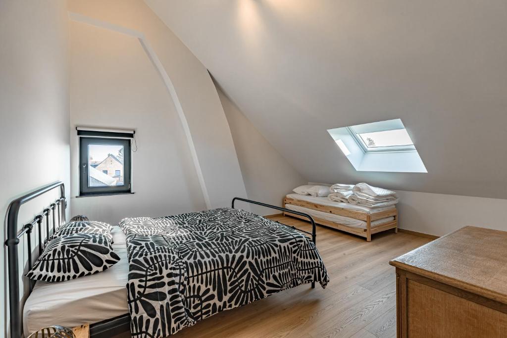 a attic bedroom with two beds and a window at Villa Victoire in Heers
