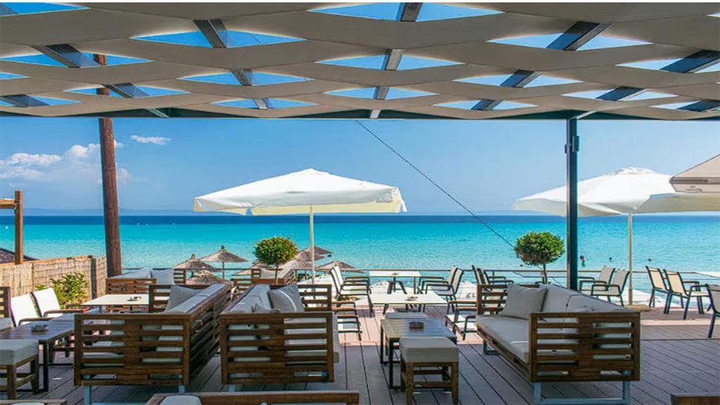 ein Restaurant mit Tischen und Stühlen und dem Meer in der Unterkunft Aya Pool Apartment in Kallithea in Kallithea (Chalkidiki)