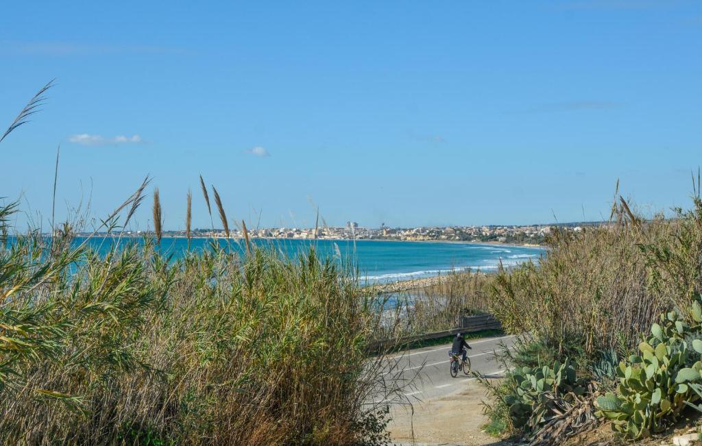 eine Person, die auf einem Weg neben dem Strand Fahrrad fährt in der Unterkunft Awesome Home In Santa Maria Del Focall in Santa Maria Del Focallo