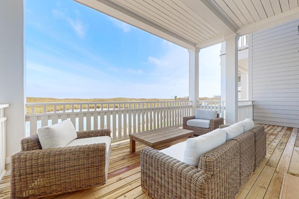 a porch with wicker chairs and a table on a balcony at Sunrise Sunset Repeat in Port Aransas