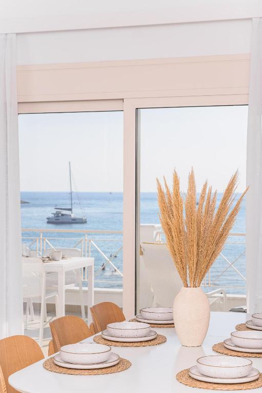 a table with white plates and a view of the ocean at BeachSide Escape Apartments in Psili Ammos