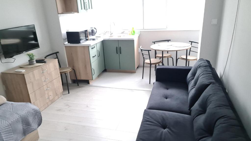 ein Wohnzimmer mit einem Sofa und eine Küche mit einem Tisch in der Unterkunft Апартаменти за Гости ИвАя Запад Казанлък in Kasanlak