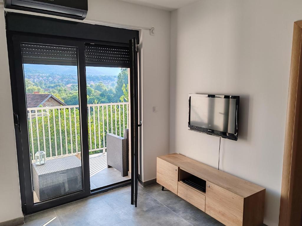 a room with a flat screen tv and a balcony at Apartman sa pogledom na Ozren in Soko Banja