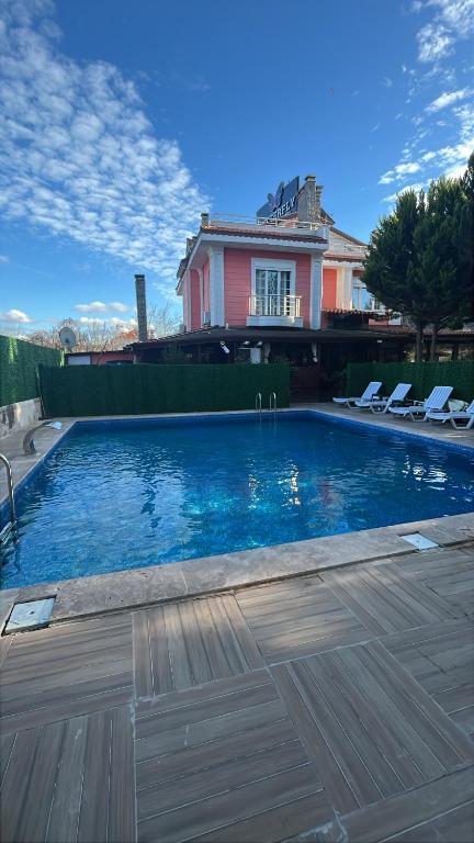 a swimming pool with chairs in front of a house at Destina Hotel Agva in Şile