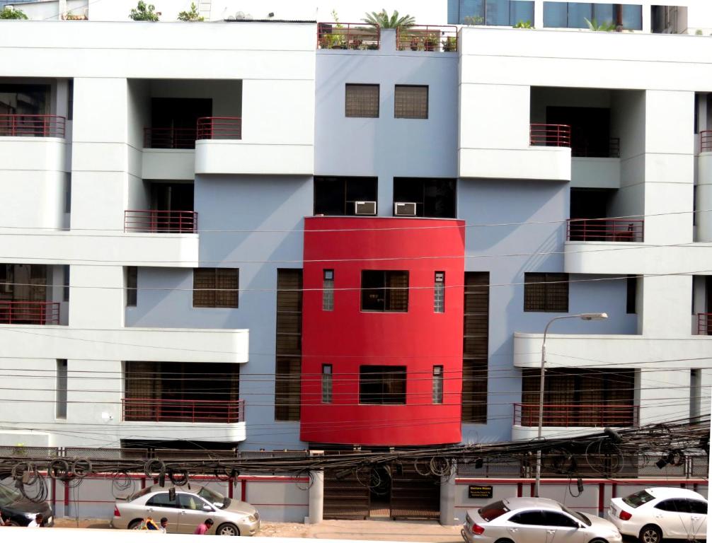 ein rotes Gebäude vor einem weißen Gebäude in der Unterkunft Eastern House in Dhaka