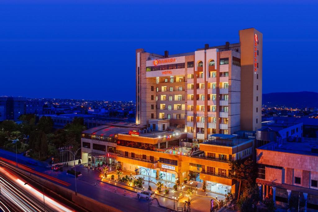 un bâtiment éclairé dans une ville la nuit dans l'établissement Ramada by Wyndham - Sulaymaniyah Salim Street, à Sulaymaniyah