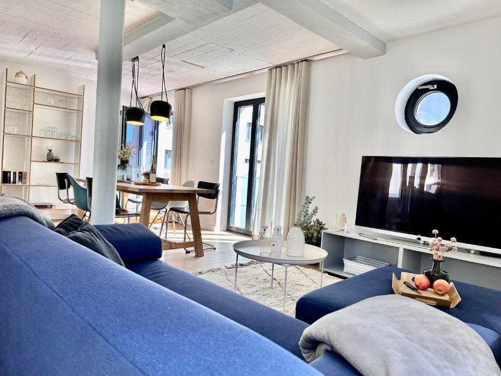 a living room with a blue couch and a tv at Ferienwohnung Dünenloft 7 im Haus Düne 7 Prora in Binz