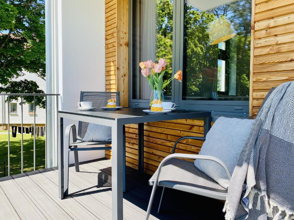 a table and chairs on a porch with a vase of flowers at Ferienwohnung Strandläufer Parkvillen Carlota und Candela Baabe in Baabe