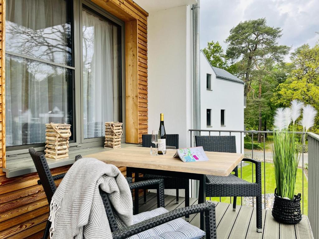 un patio con una mesa de madera y sillas en un porche en Ferienwohnung Morgensonne Parkvillen Carlota und Candela Baabe, en Baabe