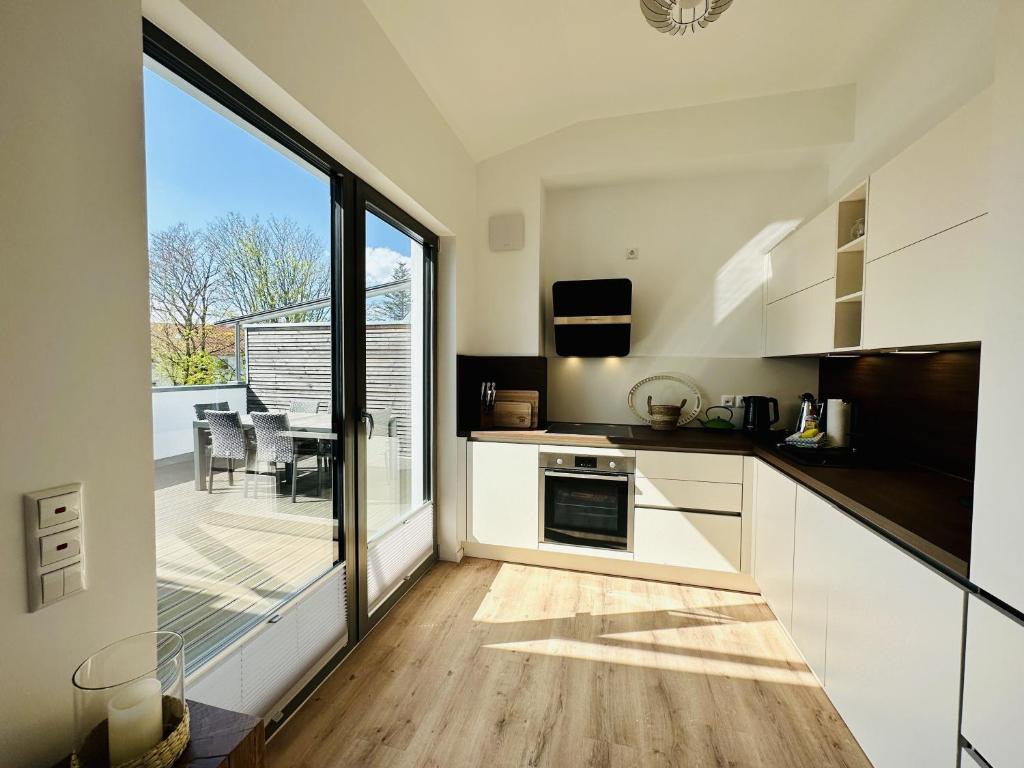 a kitchen with white cabinets and a large window at Ferienwohnung Sonnendeck Parkvillen Carlota und Candela Baabe in Baabe