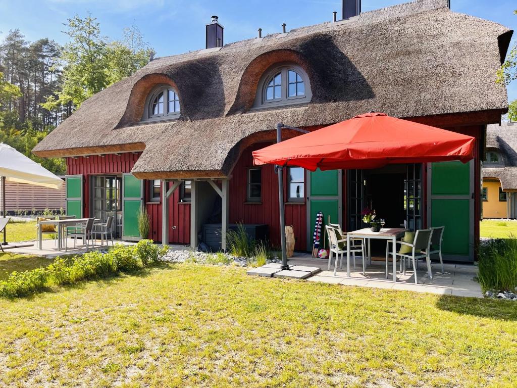 Casa con techo de paja, mesa y sombrilla en Ferienhaus "die Müllerei" 11 Feriendorf Klein Stresow Rügen by ruyastay, en Putbus