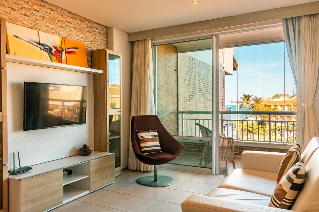 ein Wohnzimmer mit Sessel und Fernseher in der Unterkunft Porto das Dunas - Apê na Areia com Vista Espetacular, ideal para Famílias in Aquiraz