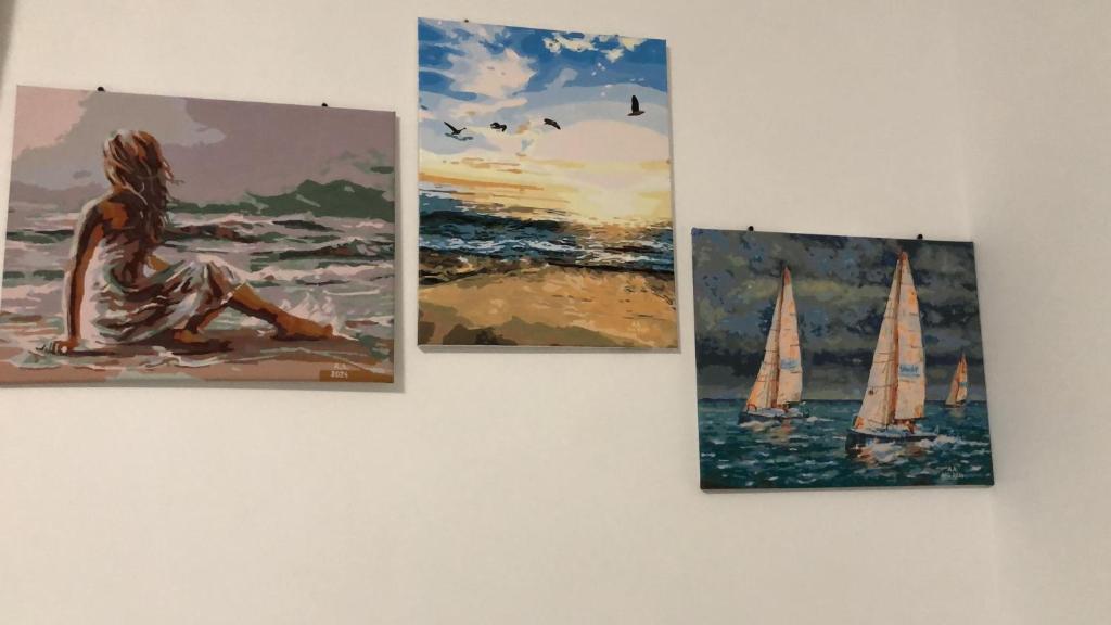 een groep van drie schilderijen aan een muur bij SUNDREAM by the beach in Mamaia