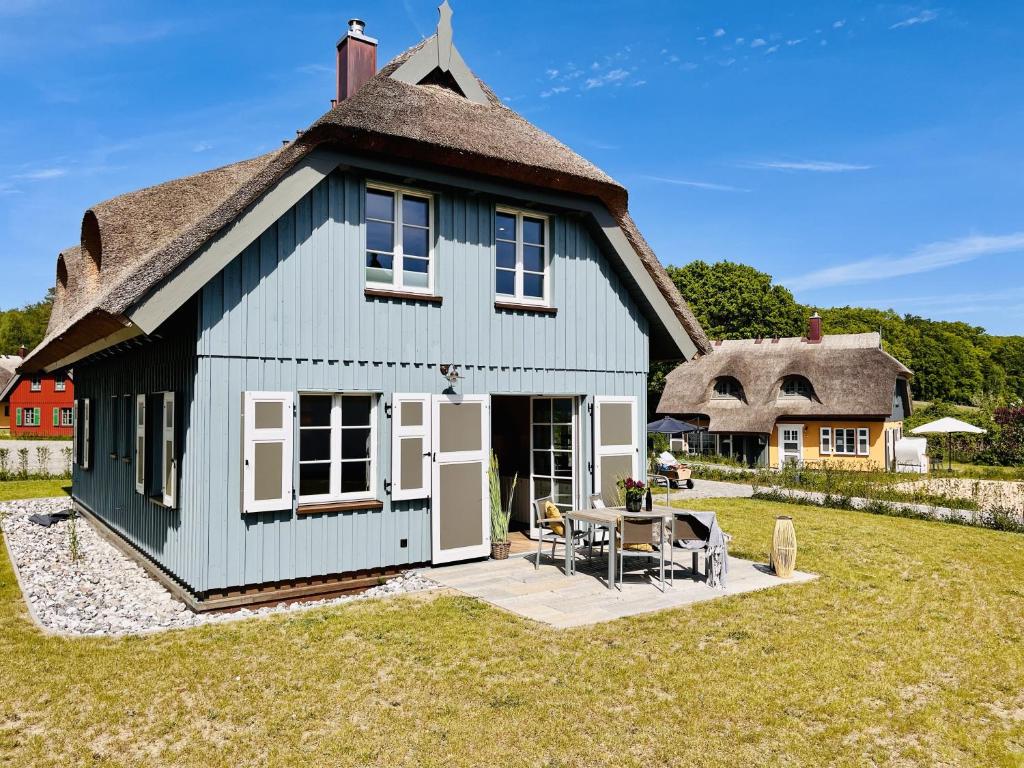 een groot blauw huis met een rieten dak bij Ferienhaus Reetblick 23 Feriendorf Klein Stresow Rügen by ruyastay in Putbus
