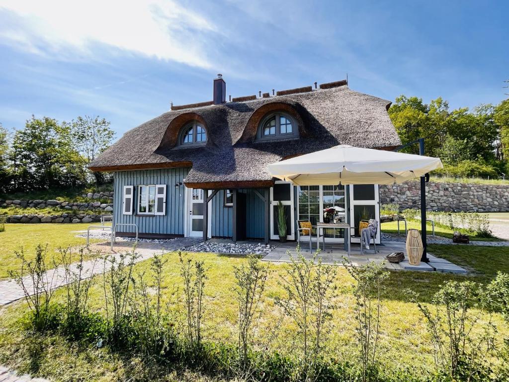 Ferienhaus Boddenlust 24 Feriendorf Klein Stresow Rügen by ruyastay في بوتبوس: منزل بسقف من القش مع مظلة