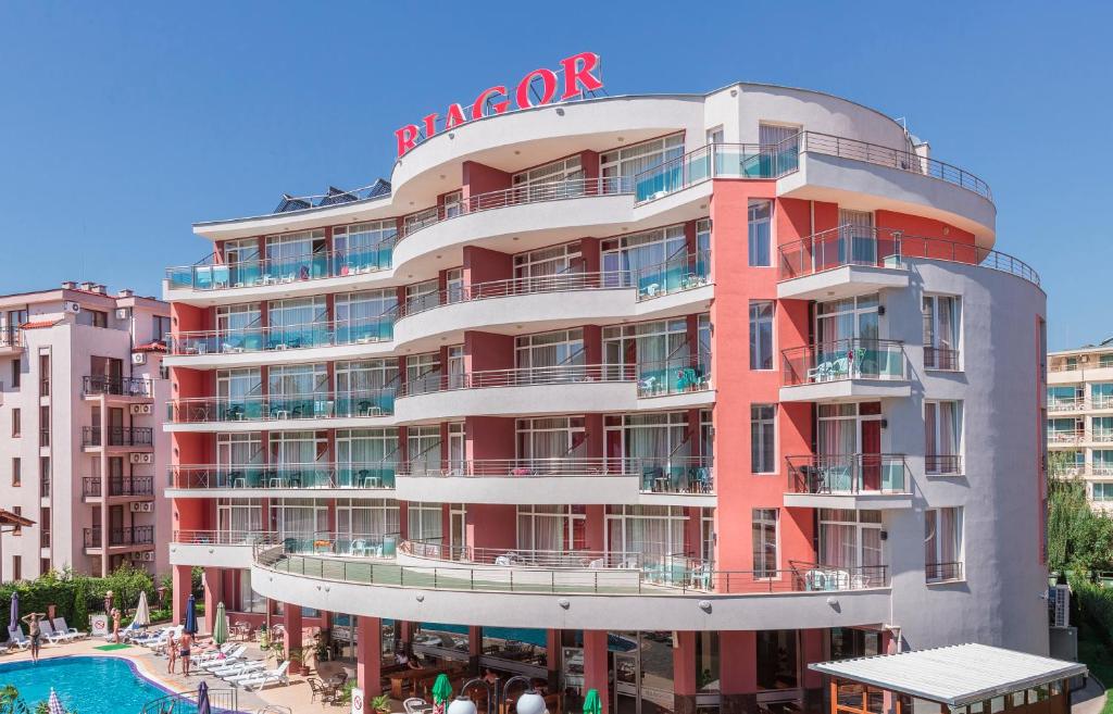 a large red building with a pool in front of it at Hotel RIAGOR in Sunny Beach