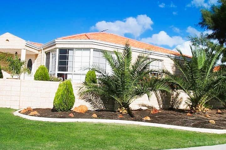 a house with palm trees in front of it at 22 Home Sweet Home Coastal Currambine in Perth