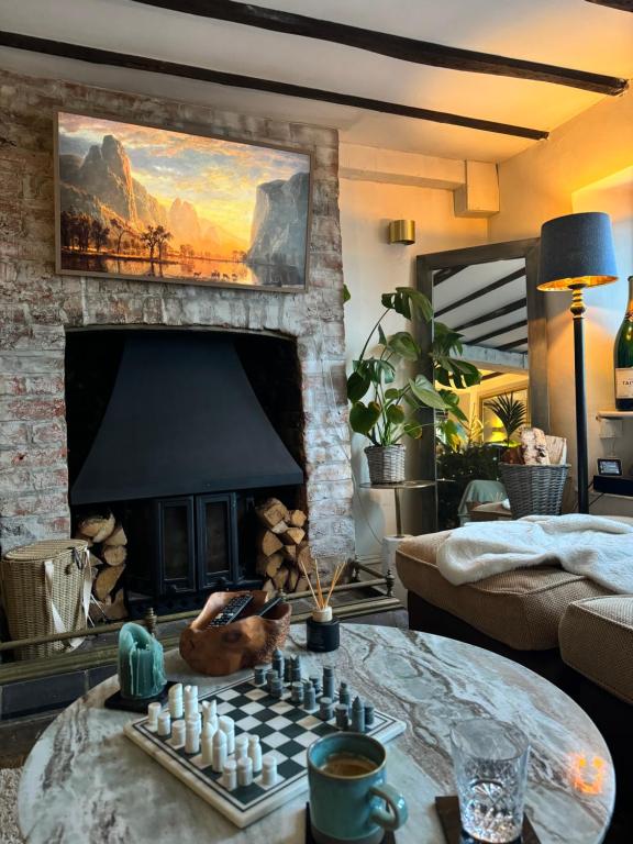 ein Wohnzimmer mit einem Schachspiel vor dem Kamin in der Unterkunft Boho Chic Cottage & Wild Garden nr Soho Farmhouse in Steeple Aston