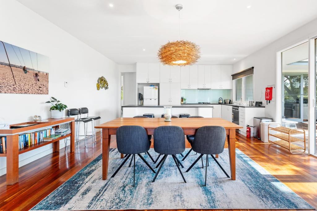 a kitchen and dining room with a wooden table and chairs at Menzies Backbeach Retreat by Ready Set Stay in Rye