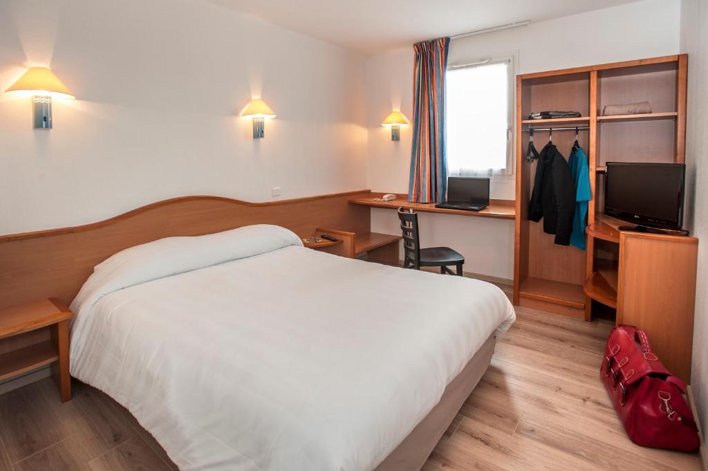 Cette chambre comprend un lit, un bureau et une télévision. dans l'établissement BRIT HOTEL Essentiel CAHORS Nord, à Cahors