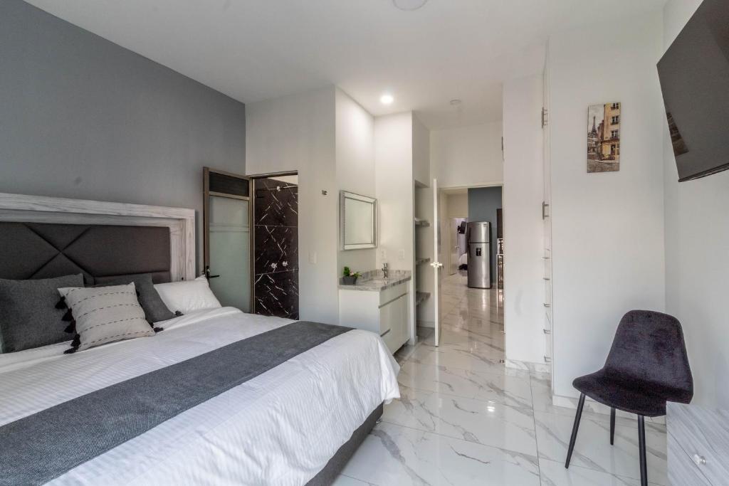 a bedroom with a large bed and a chair at Suite Balcón Refugio Moderno en Zapotlanejo 201 in Zapotlanejo