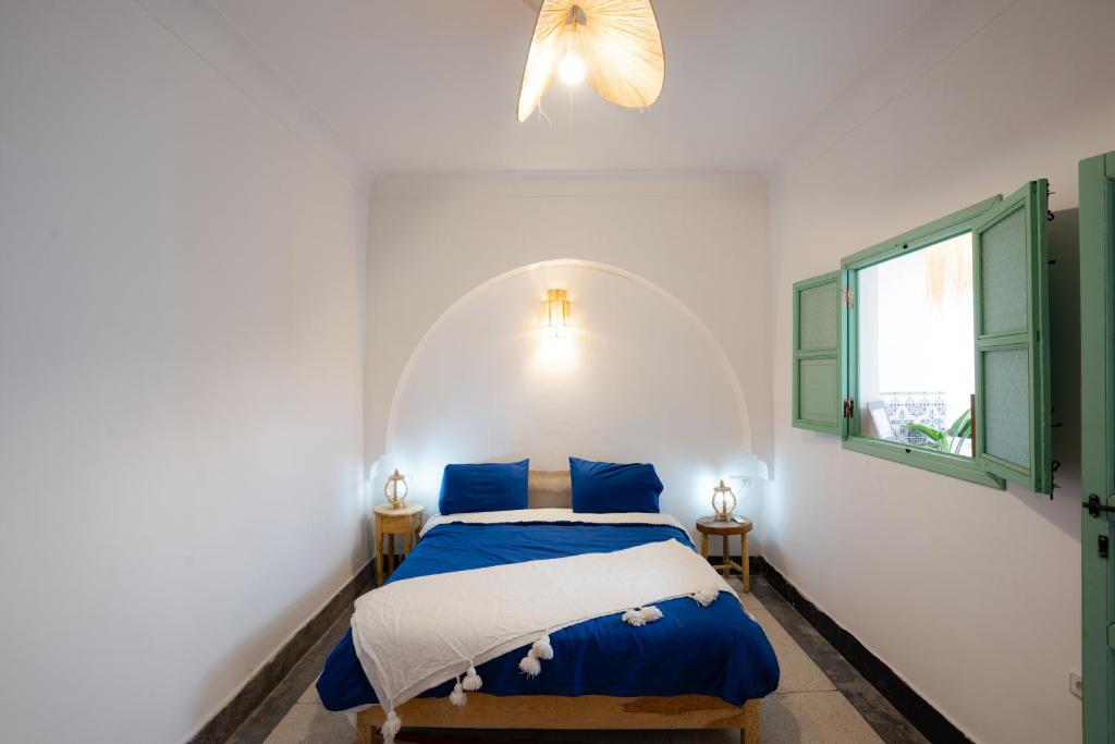 une chambre avec un lit bleu et blanc et une fenêtre dans l'établissement Riad Lkhlil, à Marrakech