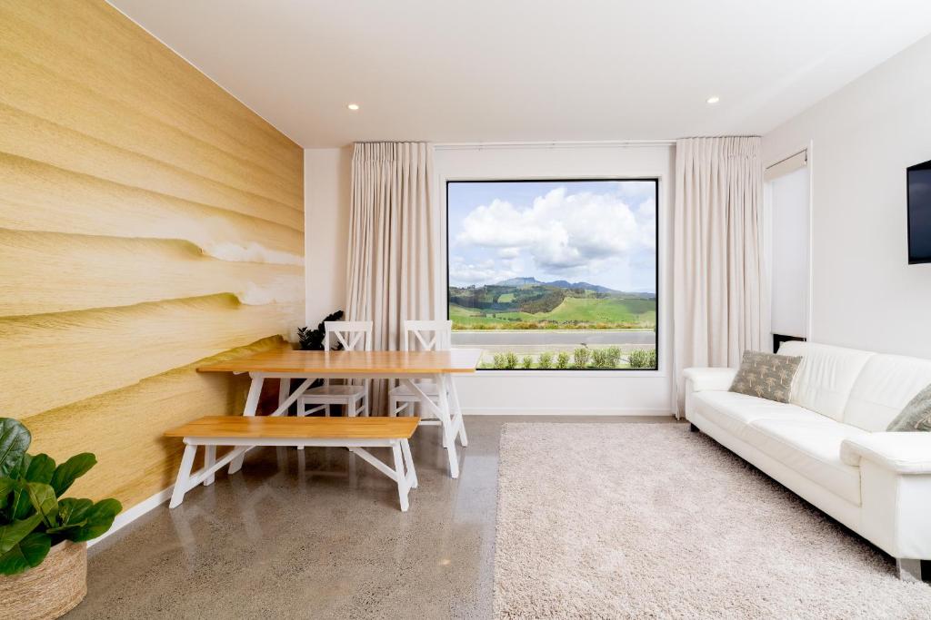 een woonkamer met een tafel en een bank bij Karioi Mountain View in Raglan