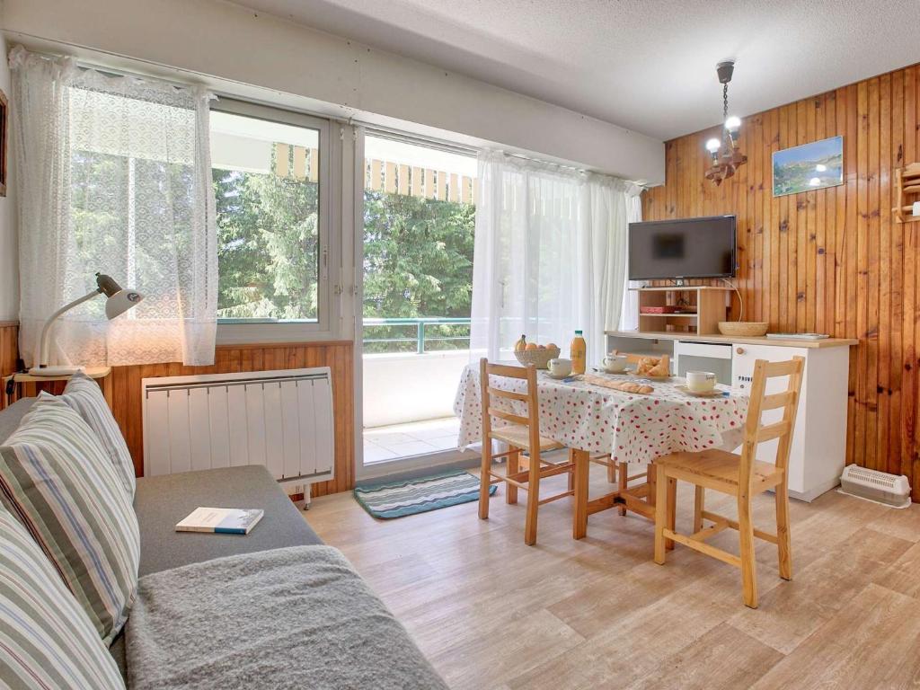 a living room with a table and chairs and a television at Appartement cosy pour 4 à Gourette, balcon sud-ouest et services optionnels - FR-1-400-134 in Eaux-Bonnes