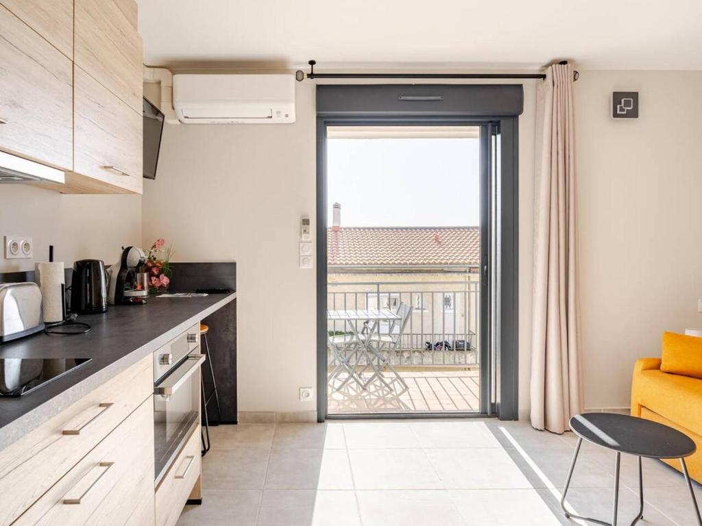 une cuisine avec une porte menant à un balcon dans l'établissement Charmant studio rénové au cœur du Lavandou avec clim et terrasse - FR-1-816-7, au Lavandou