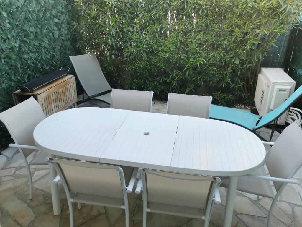 une table et des chaises blanches avec une table et des chaises blanches dans l'établissement Pavillon 6 pers avec piscine, clim, terrasses et parking privé - FR-1-781-72, à Valras-Plage