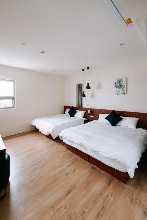 Duas camas num quarto com paredes brancas e pisos em madeira em Danny's Home em Zhongpu