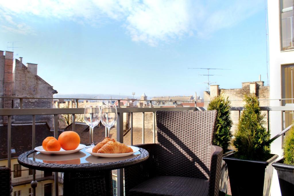 Una mesa con dos platos de comida y copas de vino en un balcón. en Broadway Center Rooftop View Apartment, en Budapest
