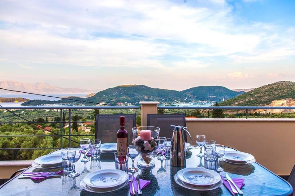 einen Tisch mit Gläsern und eine Flasche Wein auf dem Balkon in der Unterkunft Villa Maria & George in Nydri
