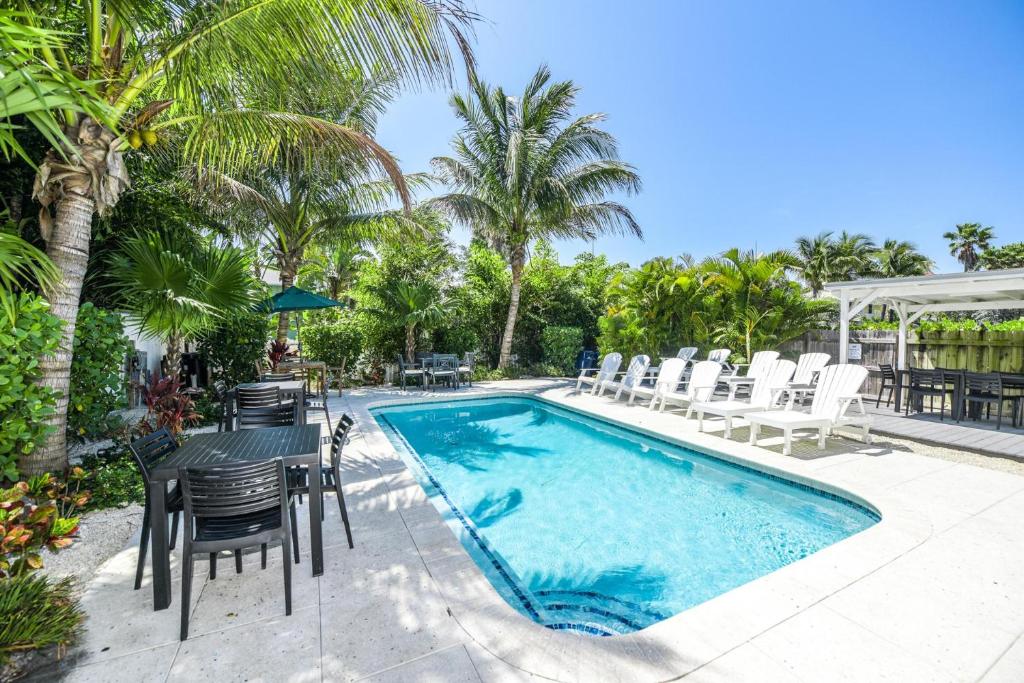 a swimming pool with chairs and a table next to a pool at Barefoot by the Bay at Bayside Bungalow in Anna Maria