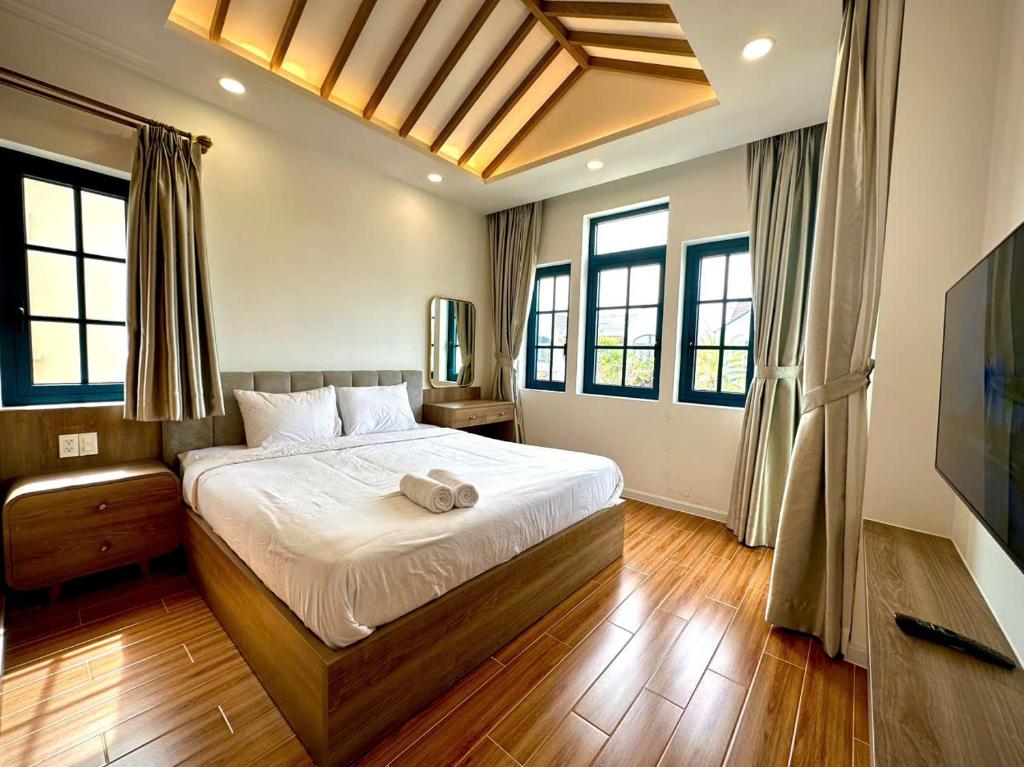 a bedroom with a large bed and windows at NOVAWORLD PHAN THIET SUNRISE VIILLA 4pn in Bình Tú