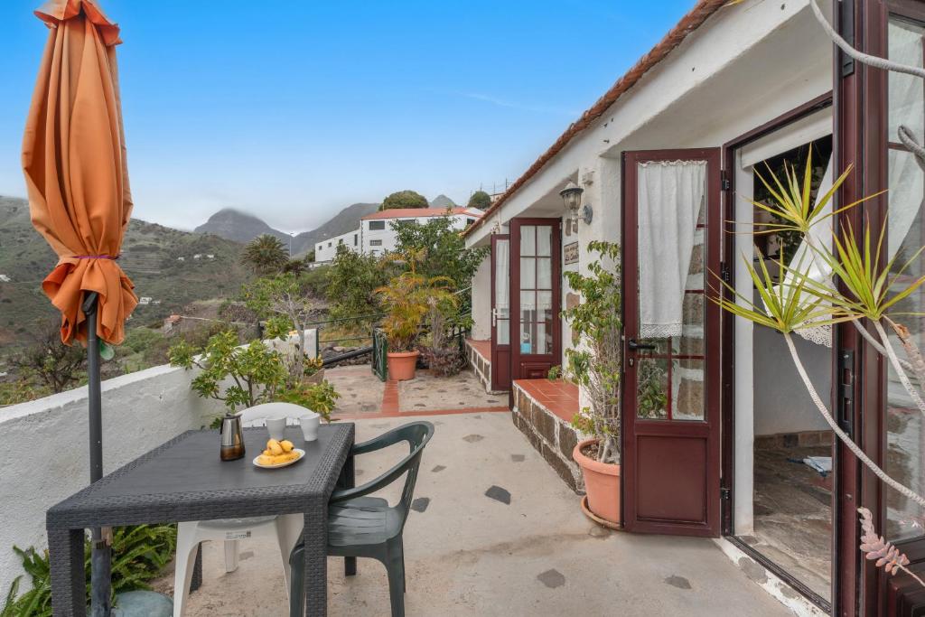 a table and chairs on a balcony with an umbrella at Casa Rural La Cuadra in Hermigua