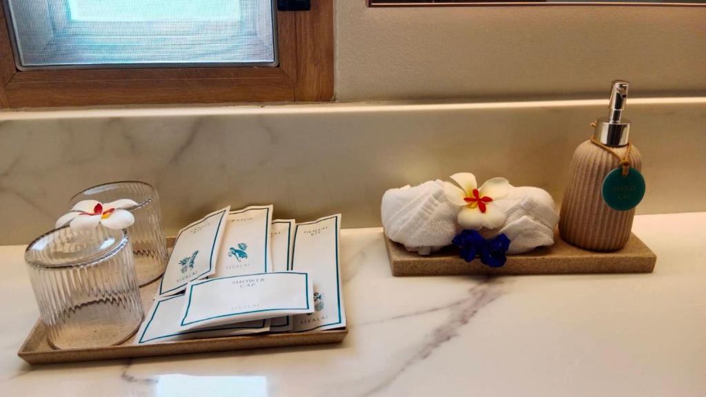 a bathroom counter with towels and books on a sink at Koh Mook Sivalai Beach Resort in Ko Mook
