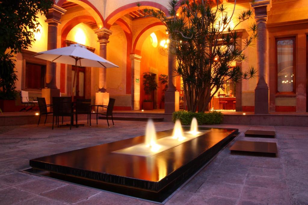 a fountain in the courtyard of a building with an umbrella at Casona de la Republica Hotel Boutique & SPA in Querétaro