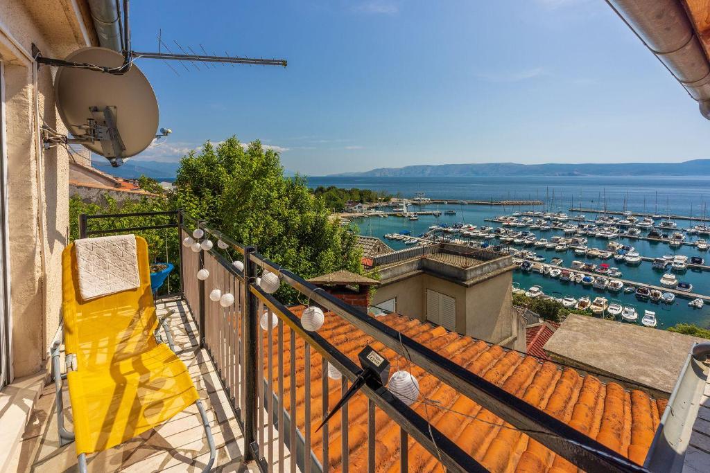 a balcony with a yellow chair and a marina at Atemberaubendes Apartment direkt am Meer gelegen mit Meerblick, Klima, WiFi in Novi Vinodolski