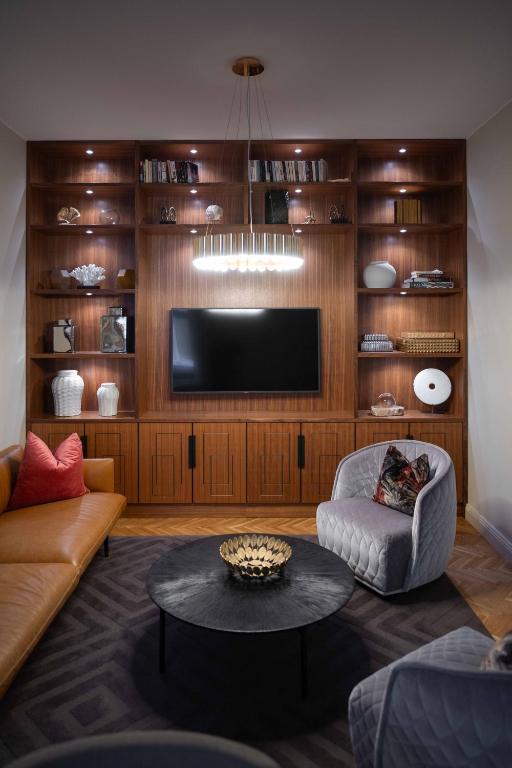 a living room with a tv and a couch and a table at Bank Hotel, a Member of Small Luxury Hotels in Stockholm