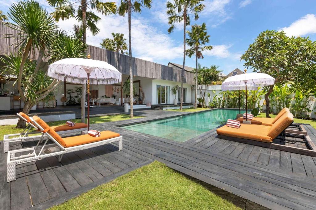 due sedie e ombrelloni accanto a una piscina di Villa Ikebana - Trendy 5BR Spacious Villa with Rice Field Views, Large Pool, and 5 Minutes to Canggu a Kerobokan